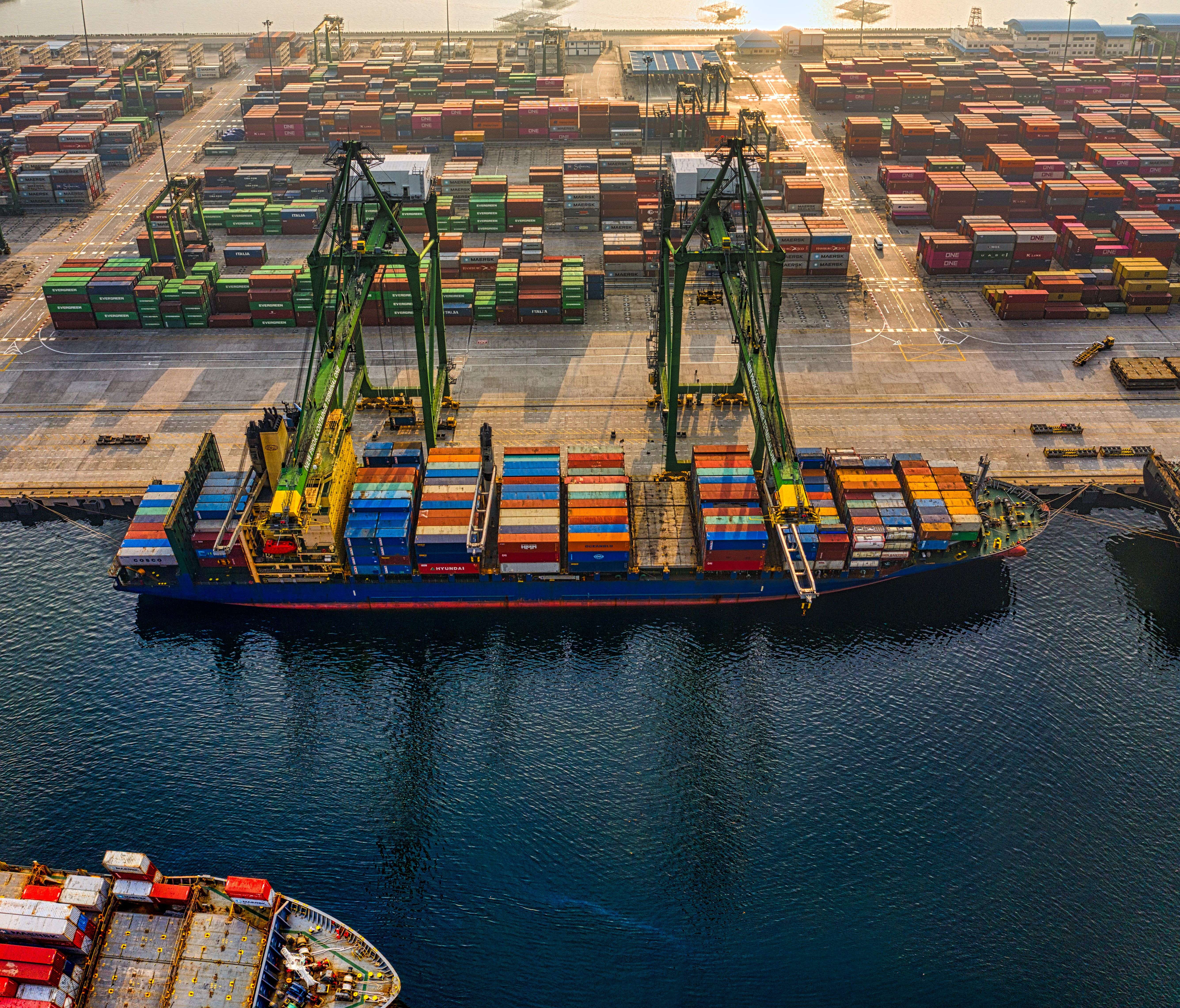 Aerial view of a container port at sunrise, cranes loading a cargo ship — the kind of large logistics site EntryBit secures
